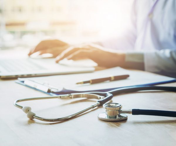 Doctor typing information on Laptop in Hospital office focus on