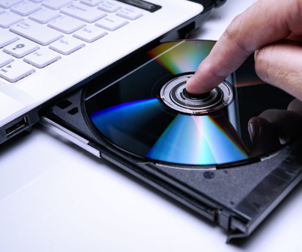 DVD Disk on the white Laptop DVD ROM Tray with a Man Hand. A Pir
