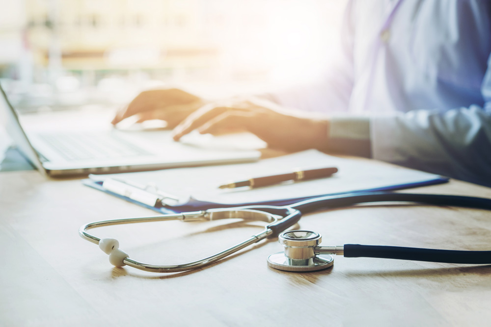 Doctor typing information on Laptop in Hospital office focus on